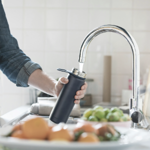 person filling water bottle from tap